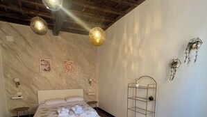 A bedroom with a bed, a chair, a shelf, and a hanging plant. - Trastevere Center, just a short walk from Piazza Trilussa (Roma)
