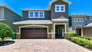 A two-story house with a garage, a small porch, and a well-maintained lawn. - Luxury Renovation-Huge Upgrades! MustSee Pool -LED Games Room! Themed Rooms! (Reunion)