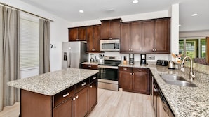 A modern kitchen with granite countertops, stainless steel appliances, and dark wooden cabinets. - Luxury Renovation-Huge Upgrades! MustSee Pool -LED Games Room! Themed Rooms! (Reunion)