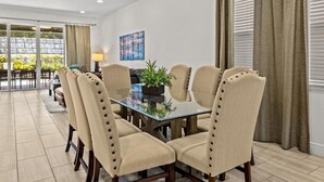 A dining area with a glass table surrounded by six upholstered chairs with button details. - Luxury Renovation-Huge Upgrades! MustSee Pool -LED Games Room! Themed Rooms! (Reunion)