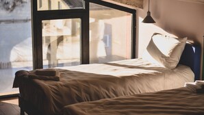 A bedroom with a large window, a bed, and a hanging light fixture. - Paliani Hostel (Mestia)