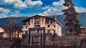 A hotel with a modern design, multiple balconies, and a view of mountains in the background. - Paliani Hostel (Mestia)