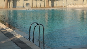 Una piscina con scalette metalliche e superficie dell'acqua cristallina.