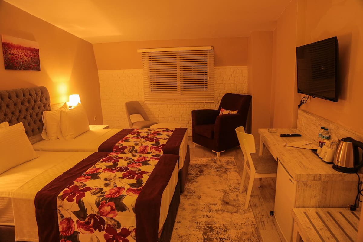 Ein Hotelzimmer mit Bett, Schreibtisch, Stuhl, Fernseher und einem Fenster mit Jalousien.