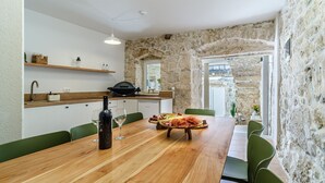 Una cocina rústica con paredes de piedra, una mesa de madera con una botella de vino y una parrilla.