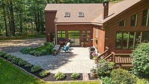 A two-story wooden house with a covered patio, a wooden deck, and a large windowed porch.