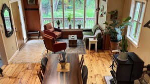 A cozy living room with a wooden floor, a dining table, and a fireplace.