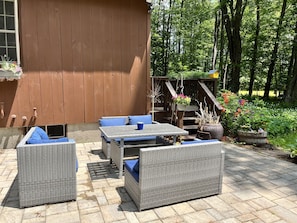 A patio with wicker furniture, a wooden deck, and a garden area with flowers and plants. - Sebago Pine Lodge +Bonus Yurt! (Windham)