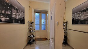 A hallway with two black-framed picture stands, a white door, and a window with blue-tinted glass. - Casa Nora Guest House (Budapest)
