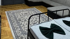 A room with a sofa, a bed, a patterned rug, and a door with windows. - Casa Nora Guest House (Budapest)