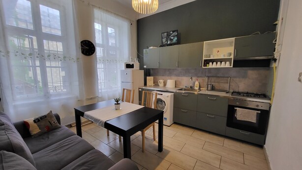 A modern kitchen with a dining area, a washing machine, and a sofa. - Casa Nora Guest House (Budapest)