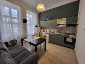 A modern kitchen with a dining area, a washing machine, and a sofa. - Casa Nora Guest House (Budapest)
