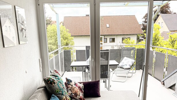 Una sala moderna con sofá, cojines, una mesita redonda y vistas al balcón exterior.