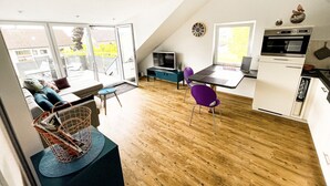 Una cocina moderna con comedor, piso de madera y ventanas amplias.