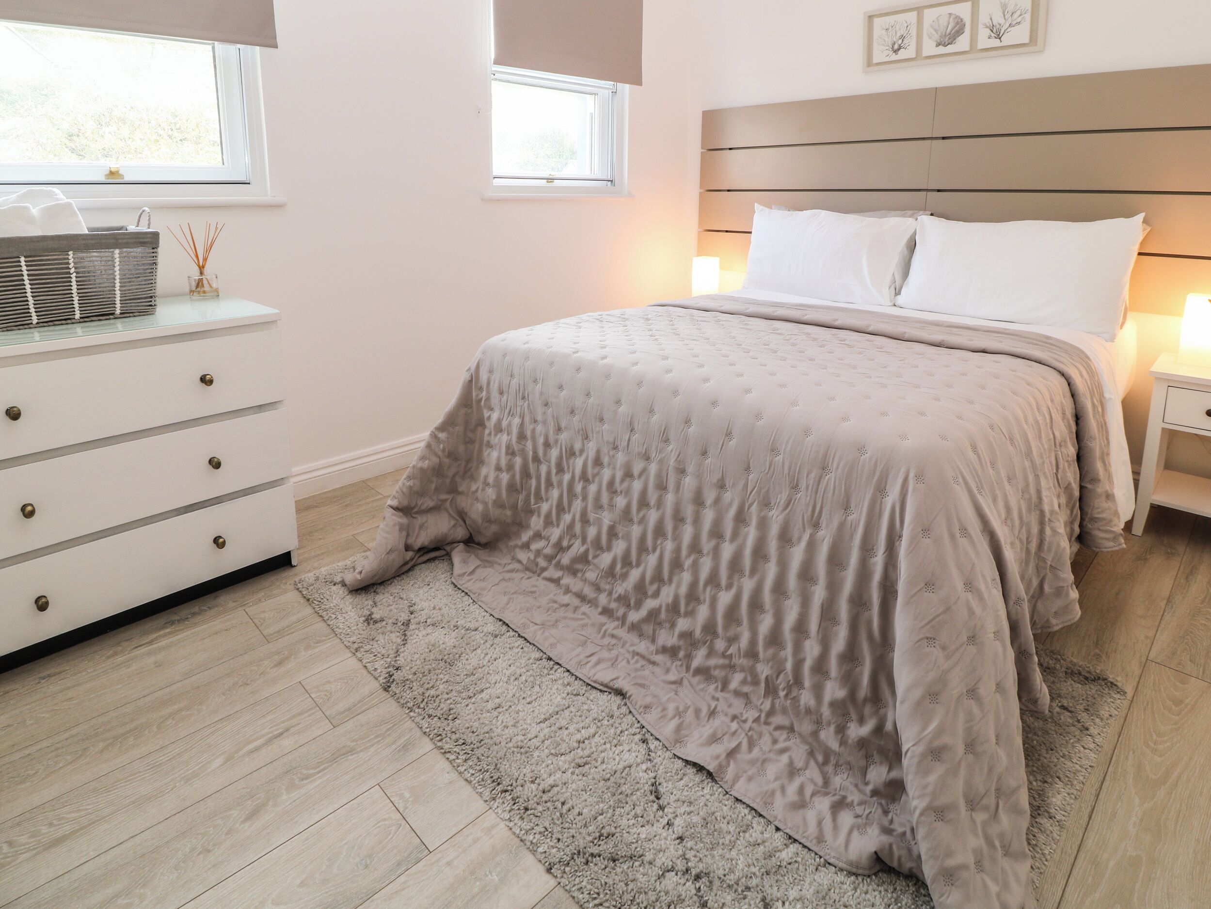 A bedroom with a bed, bedside tables, a dresser, and a window.
