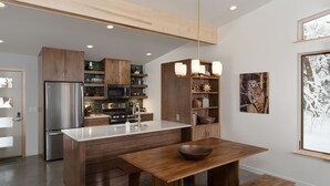 A modern kitchen with wooden cabinets, a stainless steel refrigerator, and a central island with a bowl. - Owl Ridge Cabins (Wausau)