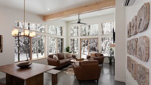 A spacious living area with a large window, a ceiling fan, and a dining table with a bowl. - Owl Ridge Cabins (Wausau)