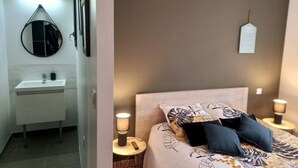 Et badeværelse med vask, spejl og et natbord med lampe.