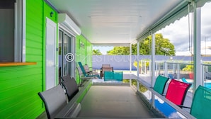 A covered porch with green walls, a bench, and outdoor seating. - Gîtes Arc-en-ciel (Saint-François)