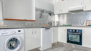 A modern kitchen with white cabinets, a built-in washing machine, a dishwasher, and an oven. - Gîtes Arc-en-ciel (Saint-François)