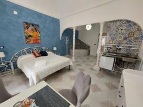 Una camera da letto con un letto, una scrivania e una sedia. Una scala conduce a un'altra stanza.
