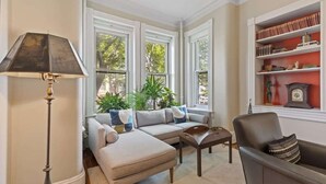 Ein Wohnzimmer mit Sofa, Sessel, Lampe und Bücherregal.