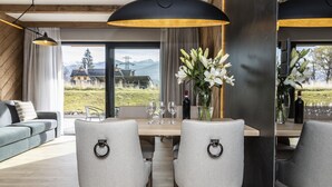 A dining area with a wooden table, grey upholstered chairs, and a vase of white flowers.