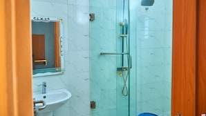 A bathroom with a glass shower enclosure, a sink, and a mirror. - Timeless Beach Resort and Hotels (Lekki)