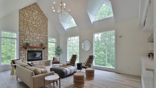 A spacious living room with a stone fireplace, large windows, and modern furniture. - 11,000sqft sleeps 29, w/ POOL! private lake, hiking trails, hot tub, 130 acres! (Logan)