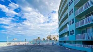 A multi-story hotel with balconies, a parking lot, and a beach view. - Ocean View Studio • Steps to Beach (Daytona Beach)