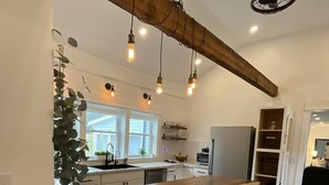 Eine moderne Küche mit einer Holztresore, Pendelleuchten und einem Blumentopf.