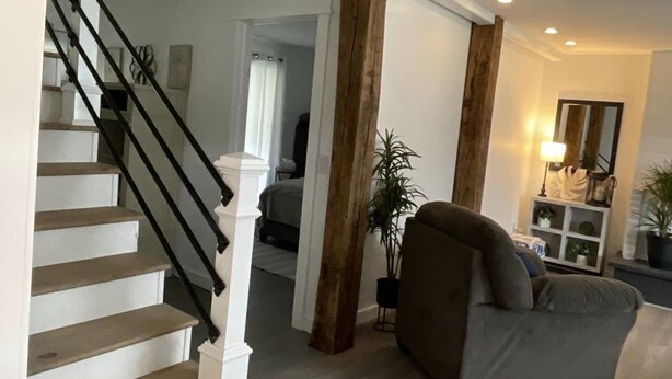 Eine Treppe mit weißen Geländern und Holzhäusern, die zu einem Raum mit einem grauen Sofa und einer Zimmerpflanze führt.