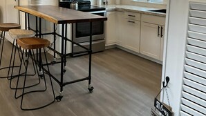 Eine moderne Küche mit einer zentralen Kochinsel, Holzbarhocker und einer hängenden Leuchte.