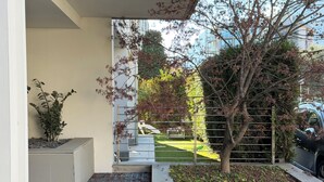 A modern building with a concrete planter, a tree, and a metal fence. - Apartment with a beautiful terrace (Riva del Garda)