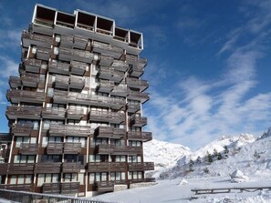 Ein mehrstöckiges Hotel mit Balkonen vor einer Bergkulisse.