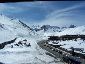 Surrounded by snow-covered mountains, this charming town offers a scenic view of a winding road through its center.