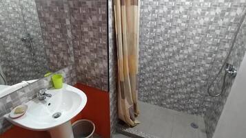 A bathroom with a white sink, a mirror, and a shower area with a tiled wall.