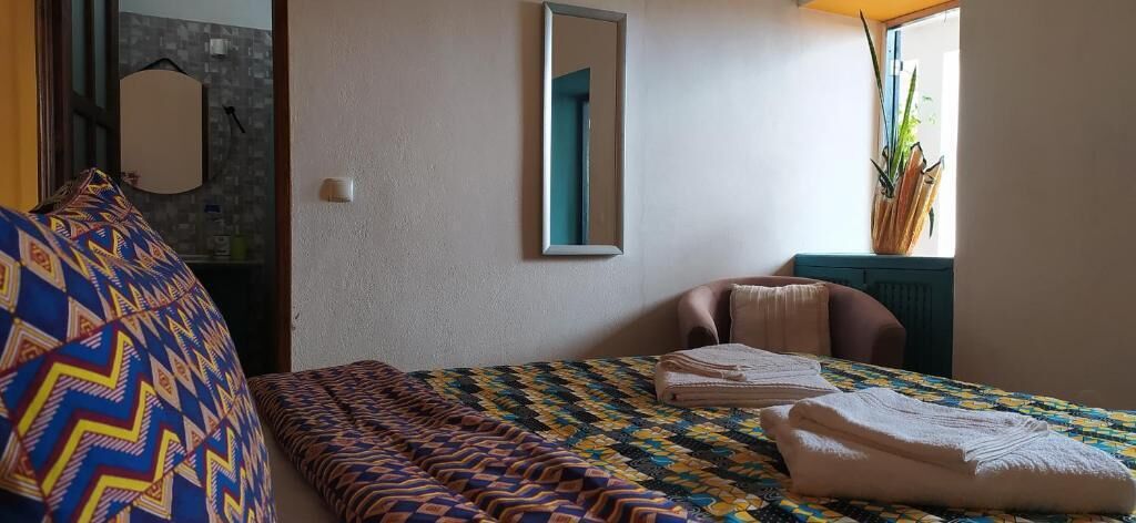 Un dormitorio con cama, una silla, un espejo y una planta.