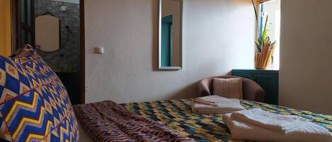 Un dormitorio con cama, una silla, un espejo y una planta.