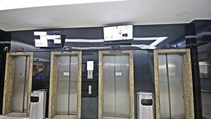 Un ensemble d’ascenseurs équipés d’écrans numériques et une poubelle placée devant.