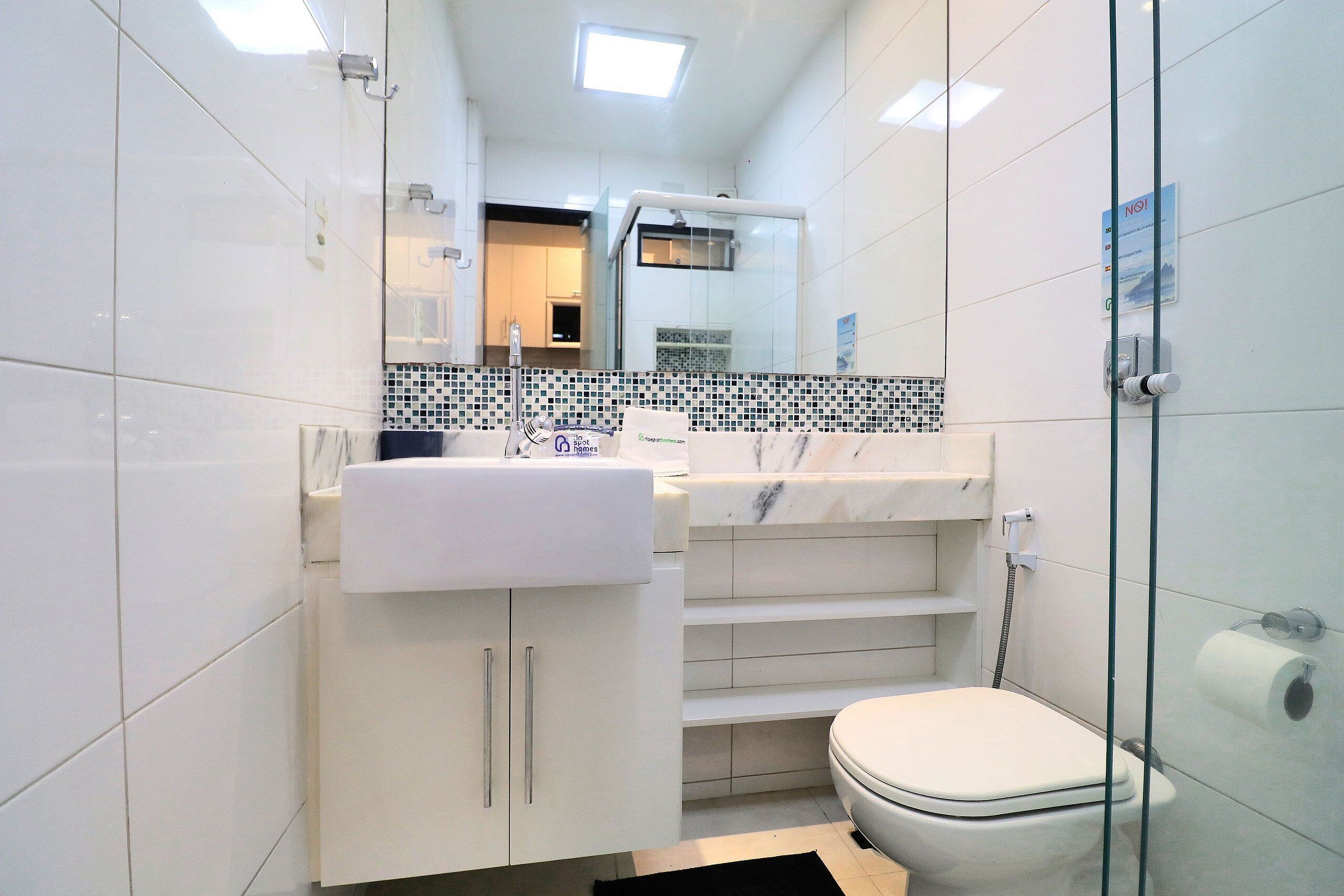 Une salle de bain moderne avec un lavabo blanc, des toilettes et une douche à parois de verre.