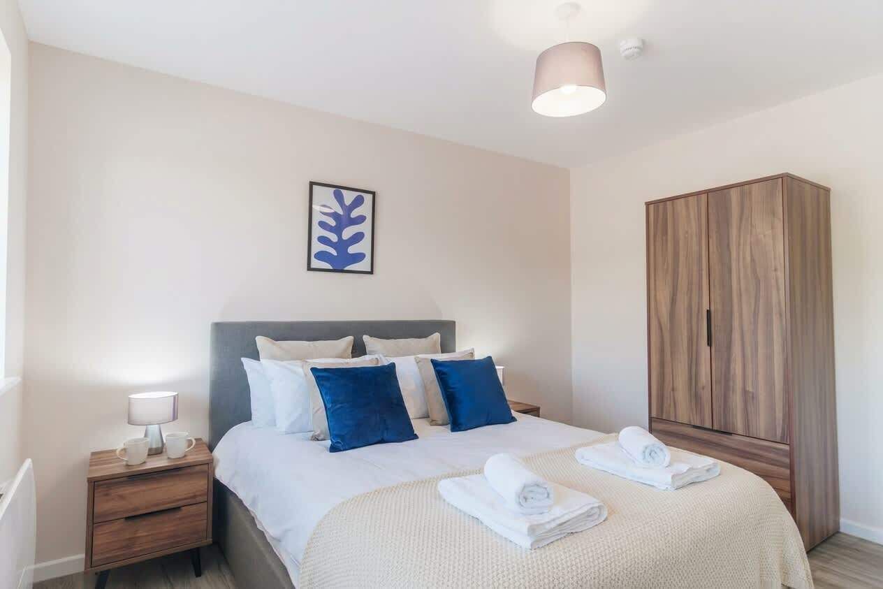A neatly arranged hotel room with a bed, bedside table, lamp, and a wardrobe.