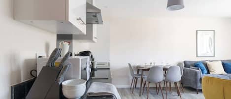 Una cocina moderna con comedor, que incluye una mesa de comedor con sillas, un sofá y una lámpara colgante.