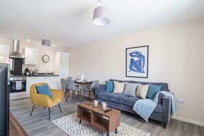 A modern living room with a sofa, coffee table, and a dining area with chairs and a table.