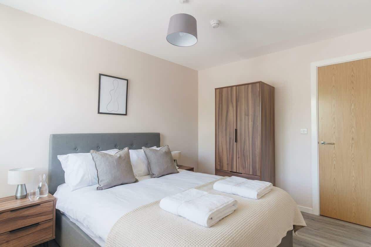 A bedroom with a bed, bedside table, lamp, and a wardrobe.
