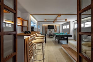 Ein modernes Zimmer mit Billardtisch, Bar und Sitzgelegenheiten.