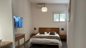 Ein Schlafzimmer mit Bett, Nachttischen, Fernseher und Fenster.