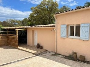 A building with a wooden pergola, a door, and a window with shutters.