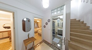 Stylish hallway leads to a bedroom with a comfortable bed and a bathroom with a glass shower enclosure.