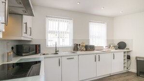 A modern kitchen with white cabinets, a built-in microwave, a toaster, and a sink. - Betty's Loft (Ambleside)